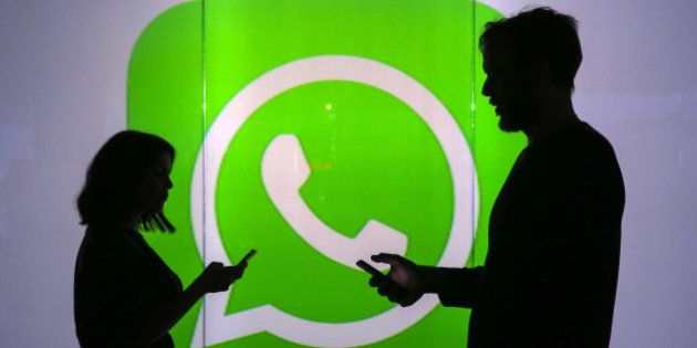 People are seen as silhouettes as they check mobile devices whilst standing against an illuminated wall bearing WhatsApp Inc's logo in this arranged photograph in London, U.K., on Tuesday, Jan. 5, 2016. WhatsApp Inc. offers a cross-platform mobile messaging application that allows users to exchange messages. Photographer: Chris Ratcliffe/Bloomberg via Getty Images