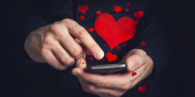 Man typing love text messages on a smartphone for Valentine's day. Selective focus on hands and phone device.