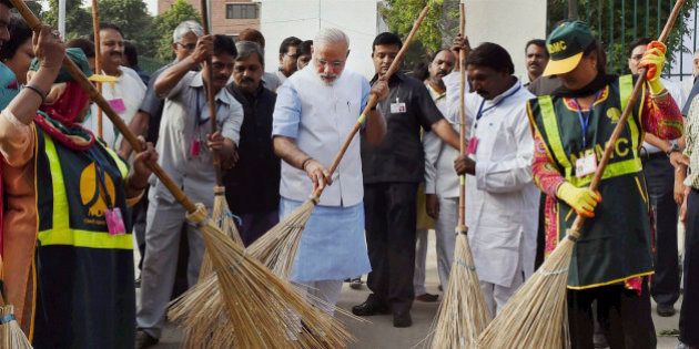 Indian Prime Minister Narendra Modi, center, sweeps an a road with a broom along with civic workers in New Delhi, India, Thursday, Oct. 2, 2014. Modi joined millions of schoolchildren, officials and ordinary people who picked up brooms and dustpans Thursday in a countrywide campaign to clean parks, public buildings and streets. (AP Photo/Press Trust of India)