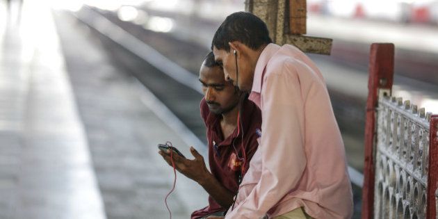 A passenger shows his smartphone screen to another passenger at Mumbai Central railway station in Mumbai, India, on Friday, Jan. 22, 2016. Google Inc. in partnership with RailTel Corp. and Indian Railways today launched high speed WiFi at the station. They plan to roll out the service to more than 400 railway stations, covering 10 million passengers each day, according to chief executive officer Sundar Pichai. Photographer: Dhiraj Singh/Bloomberg via Getty Images