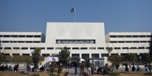 Pakistani security and media officials gather in front of the Parliament House building in Islamabad on January 6, 2015, as legislators voted for an amendment in the constitution that will protect the establishment of military courts. Pakistan's lower house of parliament on January 6 approved the setting-up of military courts to hear terrorism-related cases, after a Taliban massacre at a military-run school in the northwest shocked the nation. Prime Minister Nawaz Sharif had announced the plan after the militants gunned down 134 children and 16 adults at the Peshawar school last month. AFP PHOTO/ Aamir QURESHI (Photo credit should read AAMIR QURESHI/AFP/Getty Images)