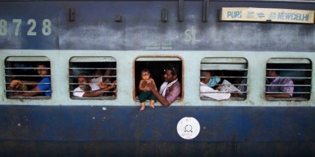 A child sits on the emergency exit window of a train, held by an adult, at a railway station in Puri, India, Tuesday, July 8, 2014. India's new rail minister Sadananda Gowda on Tuesday proposed allowing foreign investment to modernize the country's cash-strapped state railways. India has one of the world's largest railways, which transports 23 million passengers a day. Indian Railways is one of the world's biggest employers with more than 1.3 million employees. The network lost 300 billion rupees ($5 billion) last year. (AP Photo/Biswaranjan Rout)