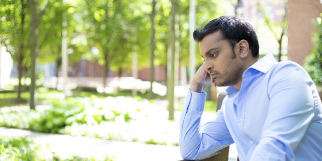 Closeup portrait, stressed young business man, resting face on fist, isolated background of trees outside. Negative human emotion facial expression feelings.