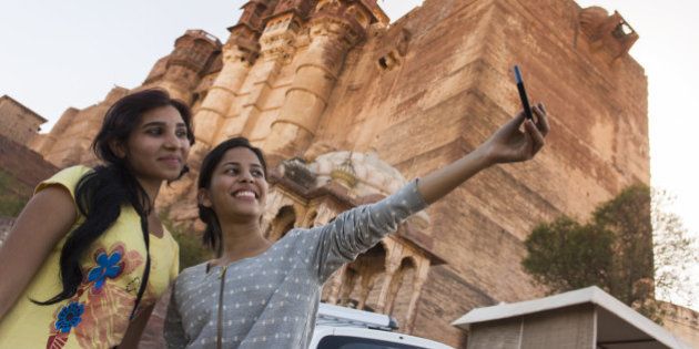 Two girls taking a tourist self portrait or selfie photo on a mobile phone at the Amber Fort.
