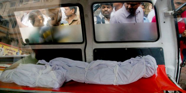 People look at the bodies of two among the victims fatally stabbed by a man as they are kept inside an ambulance outside a hospital in Thane, outskirts of Mumbai, India, Sunday, Feb. 28, 2016.A man in western India fatally stabbed 14 members of his family, including seven children, early Sunday before hanging himself, police said. (AP Photo/Rajanish Kakade)