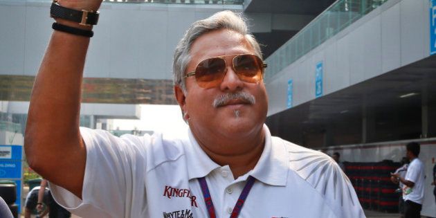 Force India team principal and businessman Vijay Mallya waves as he walks down the F1 paddock after the third practice session for the Indian Formula One Grand Prix at the Buddh International Circuit in Noida, on the outskirts of New Delhi, India, Saturday, Oct. 27, 2012. (AP Photo/Saurabh Das)