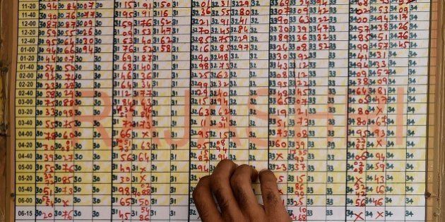 An Indian man checks the numbers of a lottery chart in Mumbai on January 1, 2015. Generally people buy lottery tickets to try out their luck on New Year's day. People all over the world ushered in the New Year 2015 with great fanfare and celebration with some offices and establishments giving a day off to their employees. AFP PHOTO / INDRANIL MUKHERJEE (Photo credit should read INDRANIL MUKHERJEE/AFP/Getty Images)