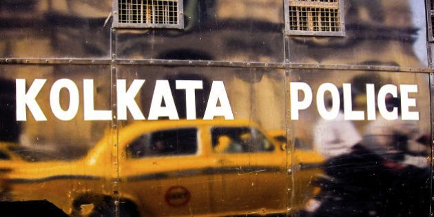 Yellow Ambassador taxi reflecting in black van with Kolkata police inscription. Calcutta, India.