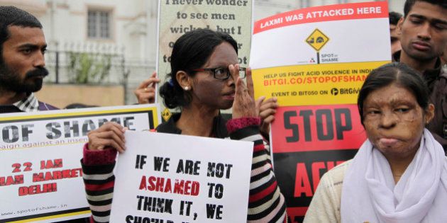 Acid attack victim Laxmi, center, holds placards with others to create awareness during a protest at the spot where she was attacked in 2005, outside the Khan Market Metro station in New Delhi, India, Wednesday, Jan. 22, 2014. (AP Photo/Tsering Topgyal)