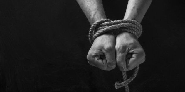 Hands tied with rope on a black background.