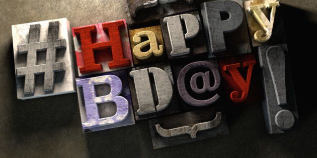 Happy Birthday title in vintage colorful wood block text. Social media hastag with grunge concrete background. Rough wooden blocks celebration of bday.