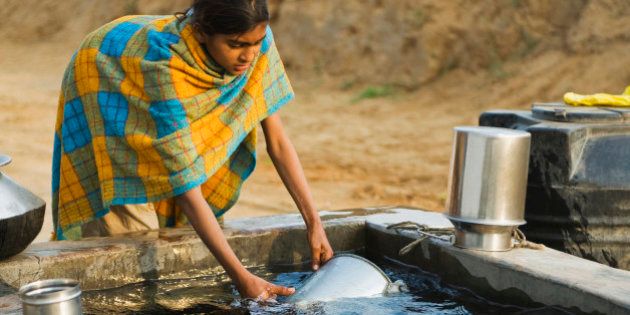 Girl cleaning pots in a tube well reservoir, Farrukh Nagar, Gurgaon, Haryana, India