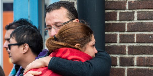People comfort each other after being evacuated from Brussels airport, after explosions rocked the facility in Brussels, Belgium, Tuesday March 22, 2016. Authorities locked down the Belgian capital on Tuesday after explosions rocked the Brussels airport and subway system, killing at least 13 people and injuring many more. Belgium raised its terror alert to its highest level, diverting arriving planes and trains and ordering people to stay where they were. Airports across Europe tightened security. (AP Photo/Geert Vanden Wijngaert)