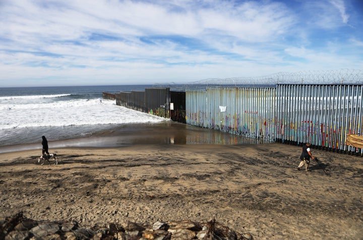 People walk on the Mexican side of the U.S.-Mexico border barrier at the Pacific Ocean on Jan. 8, 2019, in Tijuana, Mexico.