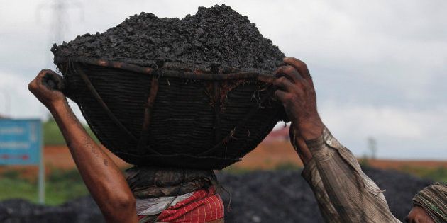 In this Monday, July 1, 2013 photo, an Indian laborer helps another with a basket of coal to load onto a truck at a roadside coal depot at Khliehriet in the northeastern Indian state of Meghalaya. Coal mines are privately owned in the state because land and resources are owned by local tribal communities. (AP Photo/Anupam Nath)
