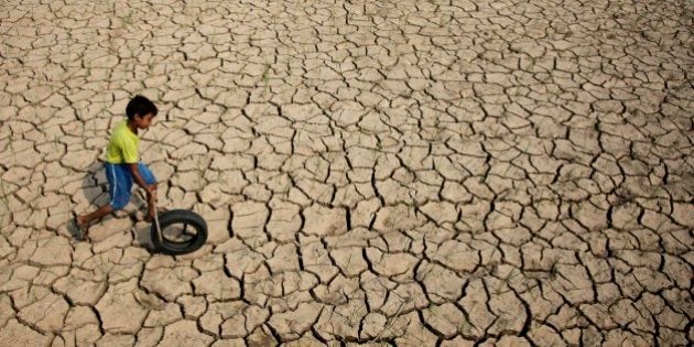 An Indian boy plays with a tire on a parched paddy field in Ranbir Singh Pura, about 34 kilometers (21 miles) from Jammu, India, Tuesday, July 15, 2014. Delayed monsoon rains have raised fears of possible drought in some regions with the meteorological department reporting an acute deficit in rainfall in many areas, according to news reports. (AP Photo/Channi Anand)