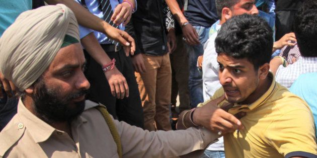 A policeman detains a student during a protest against police action on students of National Institute of Technology (NIT) in Srinagar while they were protesting against students of Kashmiri origin celebrating India's loss to West Indies in the semifinal of the ICC T20 World Cup cricket, in Jammu, India, Thursday, April 7, 2016. (AP Photo/Channi Anand)