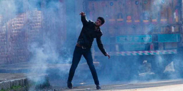 A Kashmiri Muslim protester throws back an exploded tear gas shell at Indian policemen during a protest in Srinagar, Indian controlled Kashmir, Tuesday, April 12, 2016. Two young men were killed in firing by Indian government forces at rock-throwing protesters in the town of Handwara around 80 kilometers (50 miles) north of here on Tuesday, police said. (AP Photo/Dar Yasin)