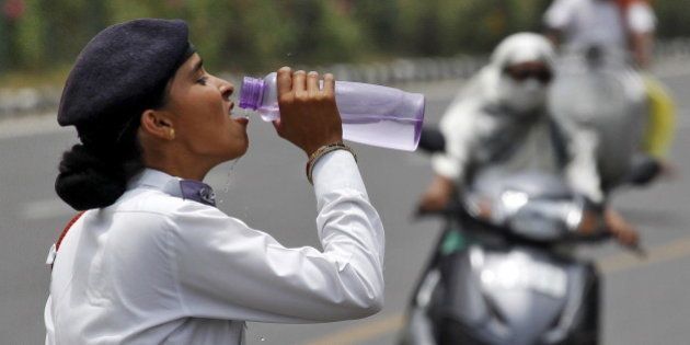 A traffic police woman drinks water as commuters drive along a road on a hot summer day in Chandigarh, India, May 31, 2015. While temperatures regularly top 40 degrees Celsius (104 degrees Fahrenheit) in May and June, parts of the south and east of India have baked under heat as high as 47 degree Celsius for seven straight days. REUTERS/Ajay Verma