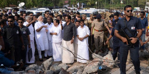 Indian Prime Minister Narendra Modi, second left, wearing white, visits the site after a massive fire broke out during a fireworks display at the Puttingal temple complex in Paravoor village, north of Thiruvananthapuram, southern Kerala state, India, Sunday, April 10, 2016. Dozens were killed and many more were injured when a spark from an unauthorized fireworks show ignited a separate batch of fireworks that were being stored at the temple complex, officials said. Most of the people died when the building where the fireworks were stored collapsed, said Chief Minister Oommen Chandy, the state's top elected official.(Press Trust of India via AP)INDIA OUT