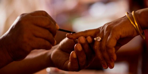 A polling official makes an ink mark on the index finger of a woman before she casts her vote during the second phase of Assam state assembly elections inside a polling station on the outskirts of Gauhati, Assam state, India, Monday, April 11, 2016. (AP Photo/ Anupam Nath)