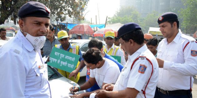 GHAZIABAD, INDIA - APRIL 15: Traffic policemen issue a challan to a commuter for driving an even-number vehicle during the 1st day of the second phase of the odd-even scheme at Delhi-Ghaziabad border, on April 15, 2016 in Ghaziabad, India. More than 500 people were challaned by Delhi Traffic Police for violating the odd-even norms in the first five hours of the second phase of the road-rationing formula implemented in the national capital on Friday. The scheme was rolled out in Delhi for the second time with chief minister Arvind Kejriwal appealing to the people of the city to join hands and make the road-rationing plan a success. The Aam Aadmi Party government implemented the first phase of the radical initiative between January 1 and 15 to clean up Delhis toxic air, considered the worst in the world. (Photo by Sakib Ali/Hindustan Times via Getty Images)
