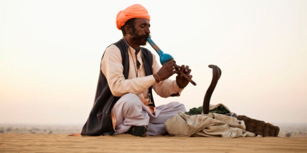 Indian Snake Charmer playing music for Cobra in Desert