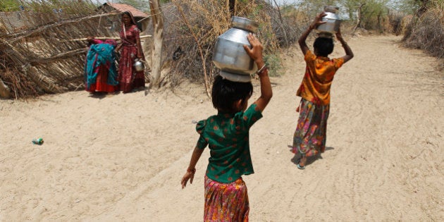 Village girls carry metal pitchers filled with water supplied by the government in the western Indian state of Gujarat April 23, 2013. India may be heading for another bumper grain harvest, if the first forecast for this year's monsoon proves correct, but the rain may be too little - and too late - for southern and western states already parched by the worst drought in four decades. REUTERS/Amit Dave (INDIA - Tags: SOCIETY ENVIRONMENT DISASTER BUSINESS)