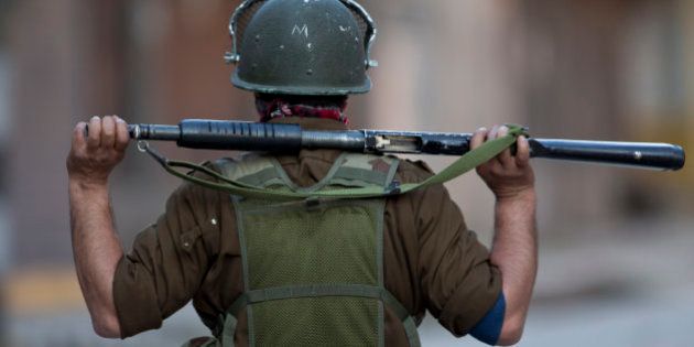 An Indian policeman looks from distance as they clash with Kashmiri Muslim protesters during a protest in Srinagar, Indian controlled Kashmir, Tuesday, April 12, 2016. Two young men were killed in firing by Indian government forces at rock-throwing protesters in the town of Handwara around 80 kilometers (50 miles) north of here on Tuesday, police said. (AP Photo/Dar Yasin)