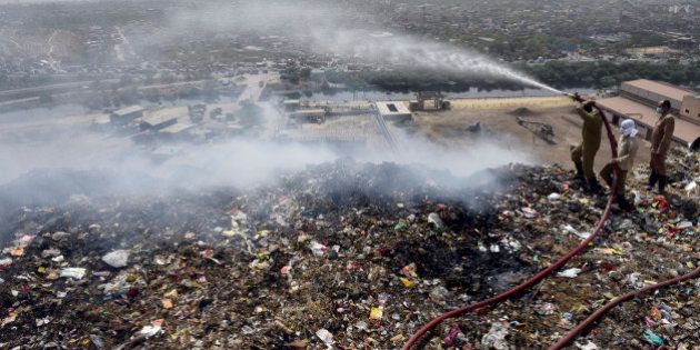 NEW DELHI, INDIA - APRIL 21: Firemen trying to douse fire at Delhi's largest landfill Bhalswa dump yard due to soaring temperature on April 21, 2016 in New Delhi, India. A large cloud of smoke was emanating from the landfill as fire tenders were dousing the fire. The 40 acre-wide trash mountain, receives about 2,700 tonnes of garbage per day. The dump yard receives garbage from no less than 50 per cent of Delhi's population, including Civil Lines, Jahangirpuri, Model Town, Kirti Nagar and even old Delhi's Chandni Chowk. (Photo by Ravi Choudhary/Hindustan Times via Getty Images)