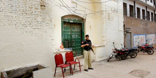 In this Monday, April 25, 2016 photo, a Pakistani policeman stands guard outside the 300-year-old gurdwara or place of worship for Pakistan's Sikh minority, in Peshawar. While Sikhs celebrated the opening of their gurdwara, its neighbors all of whom are Muslim told The Associated Press that they either didn't want them there or were worried that an attack by militants was certain to happen. (AP Photo/Mohammad Sajjad)