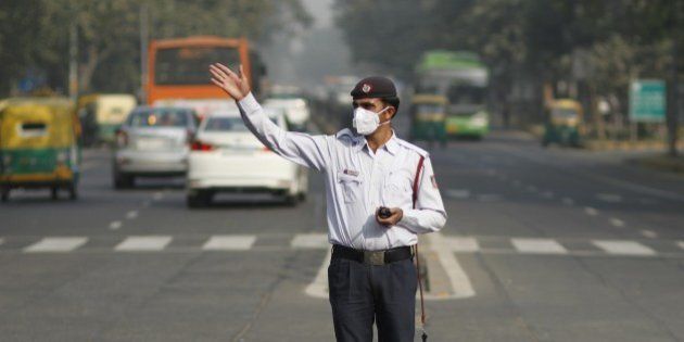 NEW DELHI, INDIA - DECEMBER 9: A traffic policeman wears anti-pollution mask while directing traffic on December 9, 2015 at Janpath Road in New Delhi. In an attempt to tackle the dangerous levels of air pollution in Delhi, Aam Aadmi Party government proposed to restrict the number of private vehicles on roads on the basis of odd-even number of their licence plates from January 1. (Photo by Arun Sharma/ Hindustan Times via Getty Images)