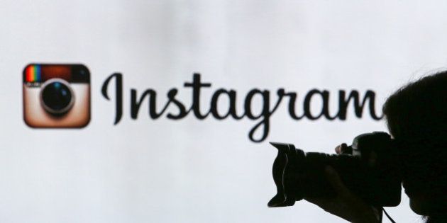 A woman takes a photograph with a digital slr camera whilst standing against an illuminated wall bearing Instagram Inc.s logo in this arranged photograph in London, U.K., on Tuesday, Jan. 5, 2016. Instagram Inc. provides mobile phone-based photography sharing services. Photographer: Chris Ratcliffe/Bloomberg via Getty Images