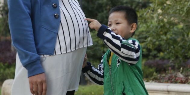 HANGZHOU, CHINA - OCTOBER 13: (CHINA OUT) A boy touches his pregnant mother's belly on October 13, 2014 in Hangzhou, China. (Photo by VCG/VCG via Getty Images)