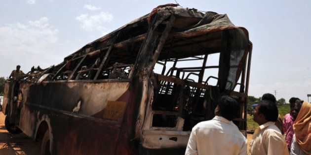 Villagers inspect a burnt-out passenger bus of the Karnataka State Road Transport Corporation (KSRTC) in Challakere village, Chitradurga district around 220 kms north of Bangalore on May 30, 2010. At least 30 people, including 10 children, were burnt alive when a bus bound for the southern Indian city of Bangalore ploughed into a roadblock and caught fire, police said. AFP PHOTO/Dibyangshu Sarkar (Photo credit should read DIBYANGSHU SARKAR/AFP/Getty Images)
