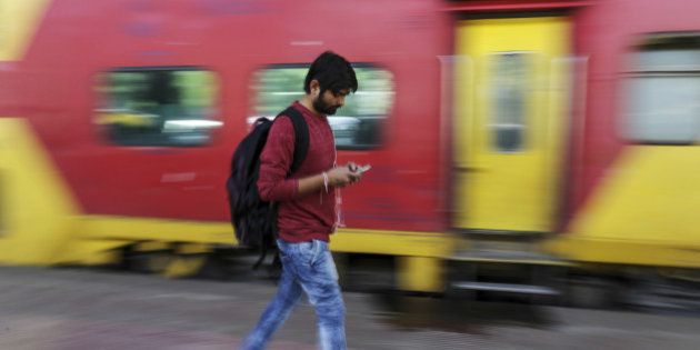 A passenger walks past a train while using a smartphone at Mumbai Central railway station in Mumbai, India, on Friday, Jan. 22, 2016. Google Inc. in partnership with RailTel Corp. and Indian Railways today launched high speed WiFi at the station. They plan to roll out the service to more than 400 railway stations, covering 10 million passengers each day, according to chief executive officer Sundar Pichai. Photographer: Dhiraj Singh/Bloomberg via Getty Images