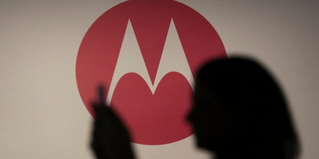 A woman takes a picture in front of a Motorola logo before the worldwide presentation of the Moto G mobile...