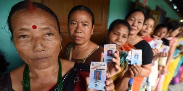 Indian voters pose for a photograph with their identity cards as they queue to cast their ballots in the state assembly elections at a polling station in Diphu in the Karbi Anglong district some 215 kms from Guwahati on April 4, 2016. Millions of Indians head to the polls April 4 in two key state elections, with Prime Minister Narendra Modi's Hindu nationalists facing a tough battle against regional rivals to tighten their grip on power. / AFP / Biju BORO (Photo credit should read BIJU BORO/AFP/Getty Images)
