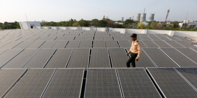 An Indian security man walks amid rooftop solar plant at the secretariat gymkhana in Gandhinagar, India, Tuesday, May 17, 2016. (AP Photo/Ajit Solanki)