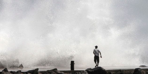 A man watches a large wave during high tide at a fishing harbour in Chennai December 28, 2011. The coastal districts in the state have been put on high alert in view of Cyclone Thane which is currently 350 km off the coast of Chennai and is likely to cross the coast on December 30, local media reported. REUTERS/Babu (INDIA - Tags: ENVIRONMENT)
