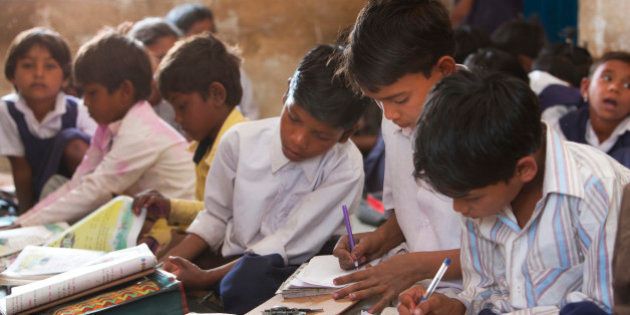 Indian schoolchildren doing their schoolwork in the classroom at their poor village school outside Bandhavgarh National Park. Children of all ages sit on the floor to do their lessons.