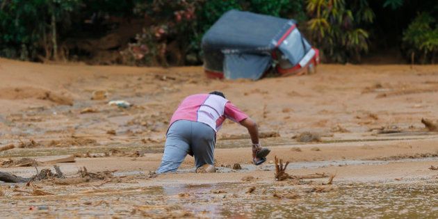 An onlooker struggles to get out after getting stuck in the mud after a landslide in Elangipitiya village in Aranayaka about 72 kilometers (45 miles) north east of Colombo, Sri Lanka, Wednesday, May 18, 2016. Soldiers and police used sticks and bare hands Wednesday to dig through enormous piles of mud covering houses in three villages hit by massive landslides in central Sri Lanka, with hundreds of families reported missing. (AP Photo/Eranga Jayawardena)