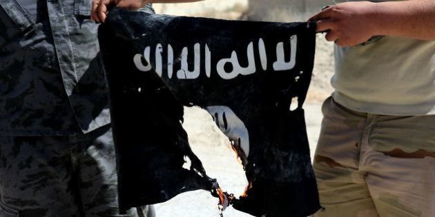 Syrian soldier sets fire on April 4, 2016 to an Islamic State (IS) group flag after Syrian troops regained control the previous day of al-Qaryatain, a town in the province of Homs in central Syria.IS jihadists withdrew from the town a week after the Russian-backed army and allied militia scored a major victory in the ancient city of Palmyra, which is also located in the vast province of Homs. The recapture of al-Qaryatain allows the army to secure its grip over Palmyra, where jihadists destroyed ancient temples during their 10-month rule and executed 280 people. / AFP / JOSEPH EID (Photo credit should read JOSEPH EID/AFP/Getty Images)