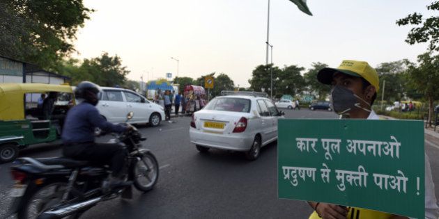 NEW DELHI, INDIA - APRIL 18: Civil defence volunteer hold a placard for general awareness about car pooling during the Odd Even second round at Rajiv Chowk on April 18, 2016 in New Delhi, India. Day four of the Delhi governments odd-even experiment began with reports of major traffic snarls emerging from various parts of the city. The second phase of the odd-even experiment was launched on April 15 to reduce the alarming levels of air pollution in the city. (Photo by Sonu Mehta/Hindustan Times via Getty Images)