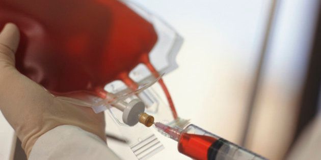 Technician drawing blood with syringe from blood bag, Close-up of hands