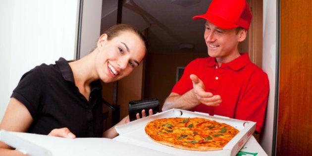 delivery boy presenting a hot pizza to a female customer at her door