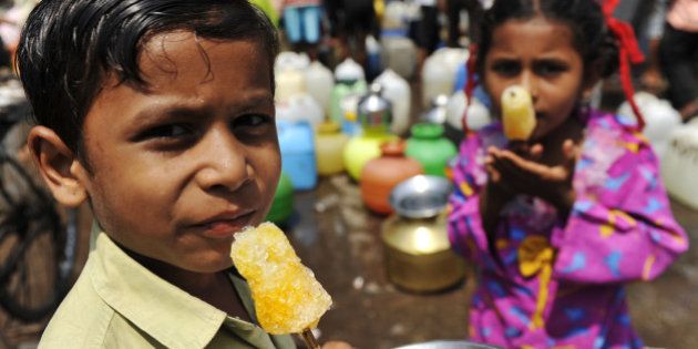 Indian children enjoy ice lollies as they wait for their mothers to fill containers with drinking water in Mumbai on World Water Day March 22, 2010. The UN has kept clean water for a healthy world as its theme this year. Demand for clean water has become critical for developing countries like India, where untreated wastewater, industrial growth and rising population make clean water a rare commodity. Mumbai city has been reeling under a water shortage since June last year, when levels at the six lakes that supply water daily to the city, started running low. Last year India suffered its worst monsoon rains since 1972, which triggered a water problem. Mumbai needs four billion litres (1.1 billion US gallons) of drinking water a day to meet the needs of its estimated 18 million residents but can currently only supply 3.3 billion litres (872 million US gallons). AFP PHOTO/ Sajjad HUSSAIN (Photo credit should read SAJJAD HUSSAIN/AFP/Getty Images)