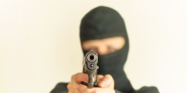 masked man points a gun