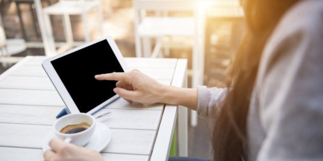 Close up shoot of a young caucasian businesswoman at the cafè during the breakfast using her digital tablet with blank screen and drinking an italian 'espresso' coffee.