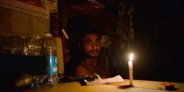 An Indian shopkeeper watches by candle-light during a power outage due to a fire which broke out at Kinari Bazar, a busy market in Chandni Chowk, the old quarters of New Delhi on August 25, 2014. Fire broke out in Kinari Bazaar in the narrow bylanes of Chandni Chowk with more than 25 fire tenders dispatched to put out the blaze. AFP PHOTO/ Chandan KHANNA (Photo credit should read Chandan Khanna/AFP/Getty Images)